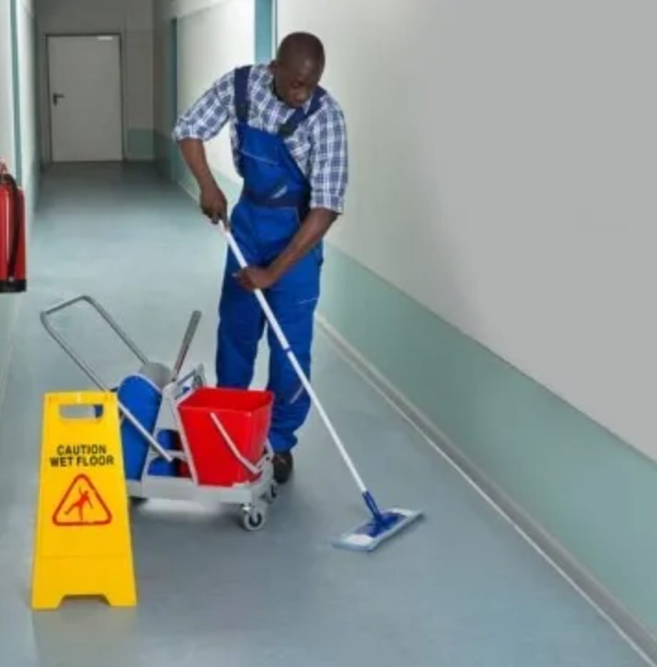Cleaner mopping a corridor with wet floor signage
